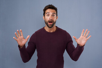 Fototapeta premium Studio, portrait and shock with hands of man, comic and wow for news of discount and announcement. Blue background, banner and space for person, surprise and confused of gossip, rumor and information