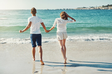 Beach, holding hands and couple with love, running and vacation for honeymoon, romance and journey. Marriage, seaside and man with woman, lens flare and adventure with support, summer and travelling
