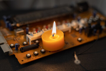 Burning candle on an electronic board. Lack of electricity due to war in Ukraine