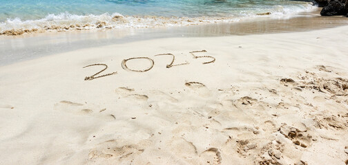 The year 2025 written in the sand at the beach