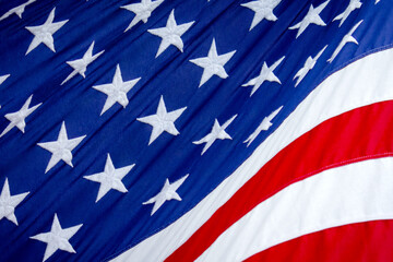 Close up of flag of United States of America while blowing in the wind while lit up by sunshine.