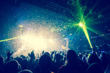 shiny confetti during the concert and the crowd of spectators with their hands up