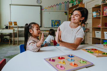 Girl and teacher playing with educational wooden toys in a kindergarten