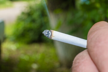 a lit cigarette in a man's hand