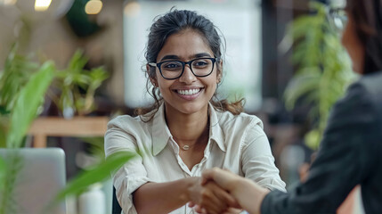 Elegant Happy Indian Businesswoman With Glasses Sitting In Her Office Chair Shaking Hands With A New Employee Who Has Just Been Hired