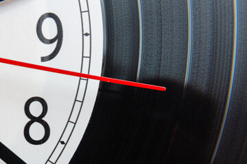 Clock vinyl record plate, arrow, backward time close-up.