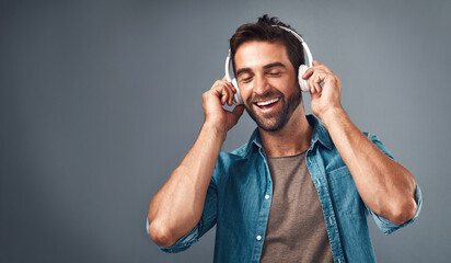 Studio, man and headphone for music, audio media and podcast or ebook on gray background. Technology, streaming and online subscription for song, male person and smile for listening with mock up