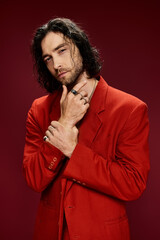 A handsome man in a red suit, exuding class and confidence, striking a pose in a studio setting.