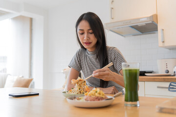 Asian Girl  eating Thai food in kitchen counter Home delivery food feeling happy 