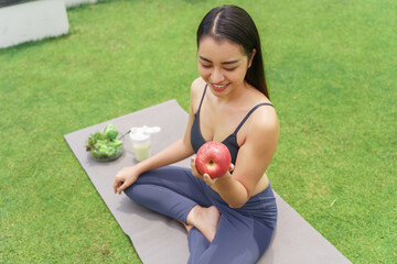 Fitness woman holding yoga mat with Fresh Apple Heathy clean vegan food before working out...