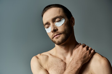 A shirtless, bearded man adorned with eye patches exudes a captivating yet mysterious aura against...
