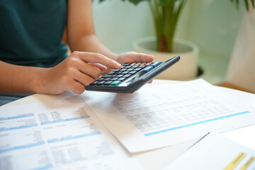 Businesswoman Accountant analyzing investment charts Invoice and pressing calculator buttons over...