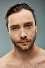 Obraz premium Close-up of a shirtless, bearded man exuding raw masculinity against a neutral grey backdrop.