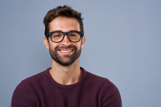 Studio, glasses and man with portrait, proud and wellness with eye care, product and lens for vision. Blue background, face and happiness for person, prescription and eyewear with fashion in USA