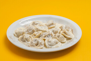 boiled dumplings on a white plate on a yellow background