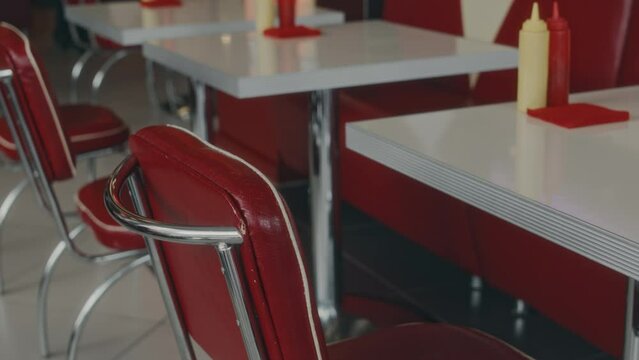 No people shot of row of red leather chairs next to empty tables in authentic vintage diner in red and white colors