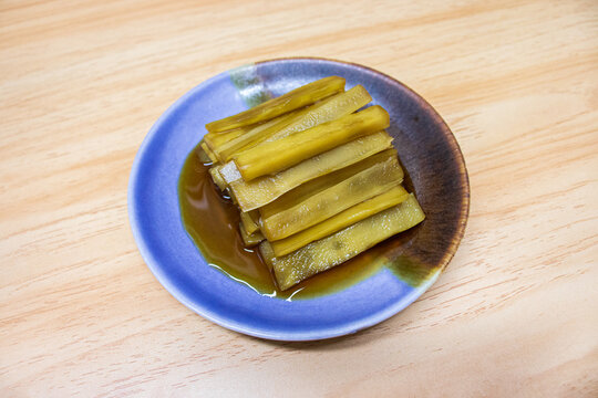 A Plate with Pickled Celtuce on a Wood Textured Background.