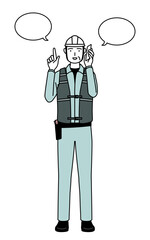 Senior male engineer in helmet and work wear pointing while on the phone.