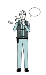 Senior male engineer in helmet and work wear operating a smartphone.