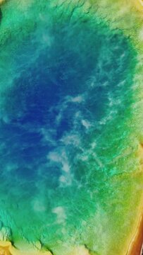 Vertical Screen: Witness the stunning colors of the Grand Prismatic Spring in Yellowstone National Park through an aerial vertical video, showcasing natures beauty and geothermal wonders