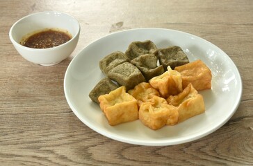 deep fried black and yellow tofu dipping with sweet crushed bean sauce on plate