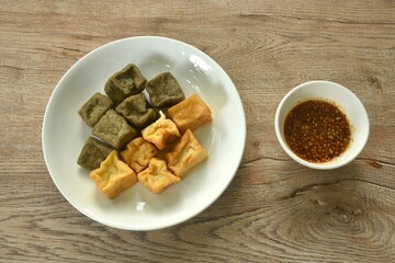 deep fried black and yellow tofu dipping with sweet crushed bean sauce on plate