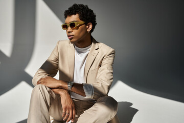 A stylish young African American man in a beige suit and fashionable sunglasses.