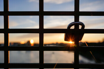 Close up of a padlock hanging from a bridge during sunset