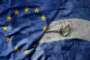 big waving realistic national colorful flag of european union and national flag of el salvador on a euro money banknotes background.