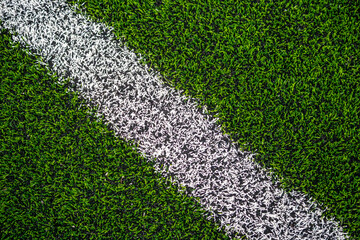 Artificial grass or turf from a football field with a white line painted on © Matt