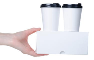 Two cup of coffee and box with desserts take away in hand on white background isolation