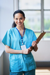 Smiling Female Doctor Holding Clipboard in Bright Hospital Corridor