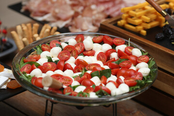 Shallow depth of field (selective focus) details with tomatoes, mozzarella and basil salad at a buffet.