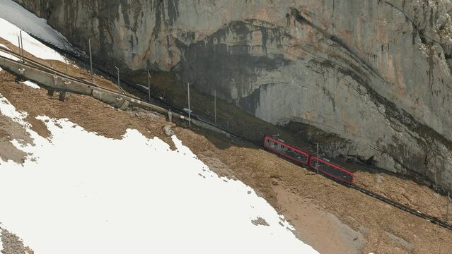 Red funicular railcar train driving through Pilatus mountain in Swiss Alps