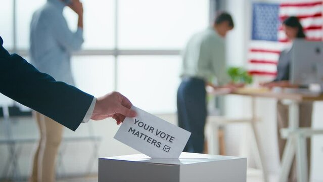 Close up of hand putting slip of paper at polling station for American election with voters - shot in slow motion
