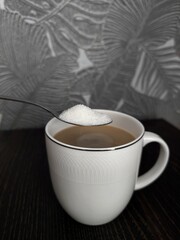 Adding sugar into th cup of coffee, white mug