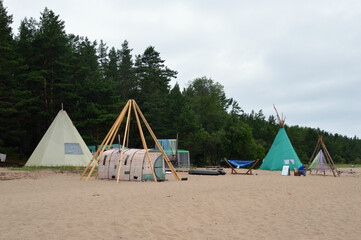Tourist tepee on sand near forest.