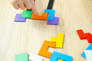 Toddler's hands manipulate colorful wooden geometric pieces intellectual puzzle, smart child solves...