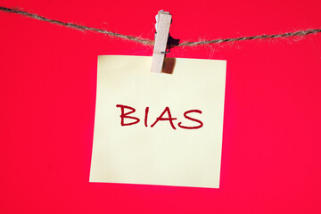 Business bias concept. Word BIAS written on a yellow sticker suspended from a rope in front of a...