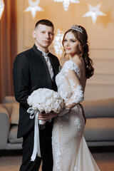 A bride and groom are posing for a picture in a room with a starry background. The bride is wearing...