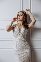 A woman in a white dress with a tiara on her head poses for a photo. Concept of elegance and...