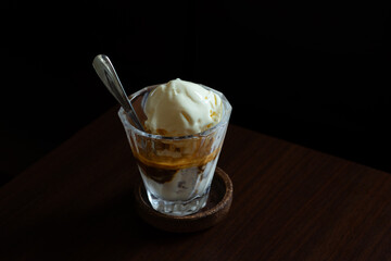 affogato dessert served on transparent glass, over dark wooden table background
