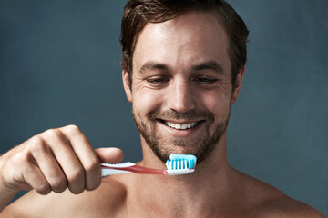 Hygiene, man and toothbrush topless in studio background with smile for dental health, wellness or mouth care. Male person, happy and oral product isolated backdrop for clean teeth and fresh breath