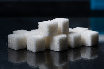 Pile of refined sugar cubes dark background.