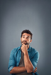 Portrait, thinking and man with ideas, solution and problem solving on grey studio background. Face, person and model with questions, mockup space and opportunity with choice, decision and remember