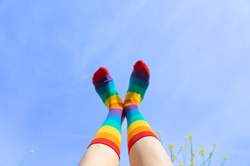 Feet with LGBTIQ flag socks with a blue sky in the background
