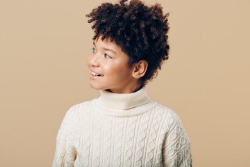 Portrait of a young african american girl in a cozy white sweater posing gracefully against a soft...