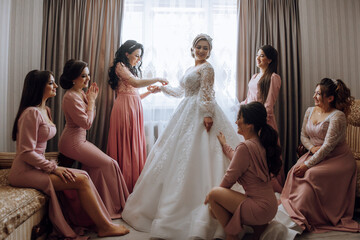 A group of women are getting ready for a wedding. One of the women is getting her dress altered