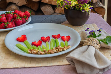 Dish with strawberries in the form of flowers in the shape of hearts, spring flowers on the table
