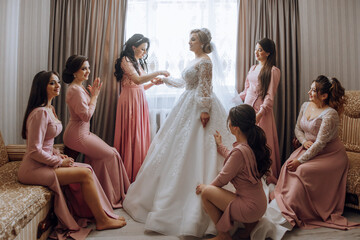 A group of women are getting ready for a wedding. One of the women is wearing a white dress